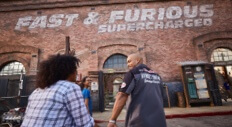 Guests at Universal Studios Florida head toward the Fast & Furious Supercharged ride entrance, a large industrial looking brick building.
