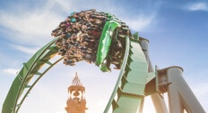 A group of guests on The Incredible Hulk Coaster cheer as they round a curve.