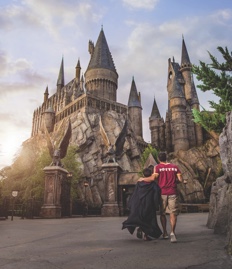 A father and son walk toward the Hogwarts castle in the Wizarding World of Harry Potter - Hogsmeade.
